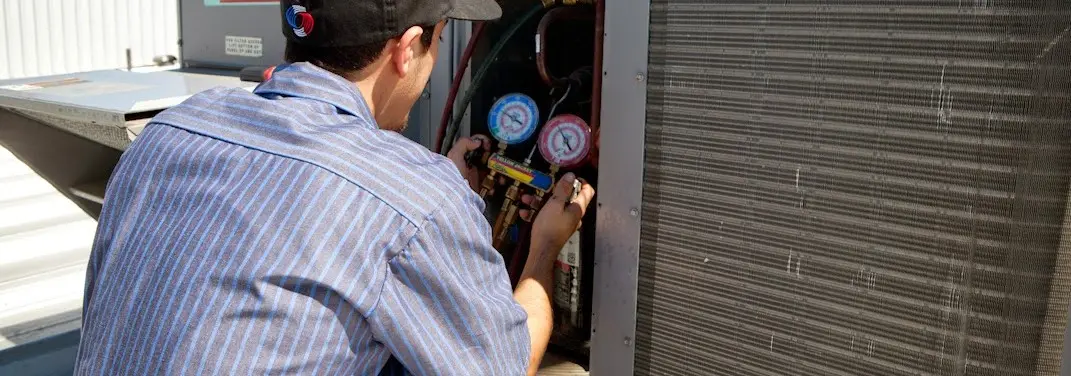 HVAC technician servicing a condenser unit in Columbia Falls